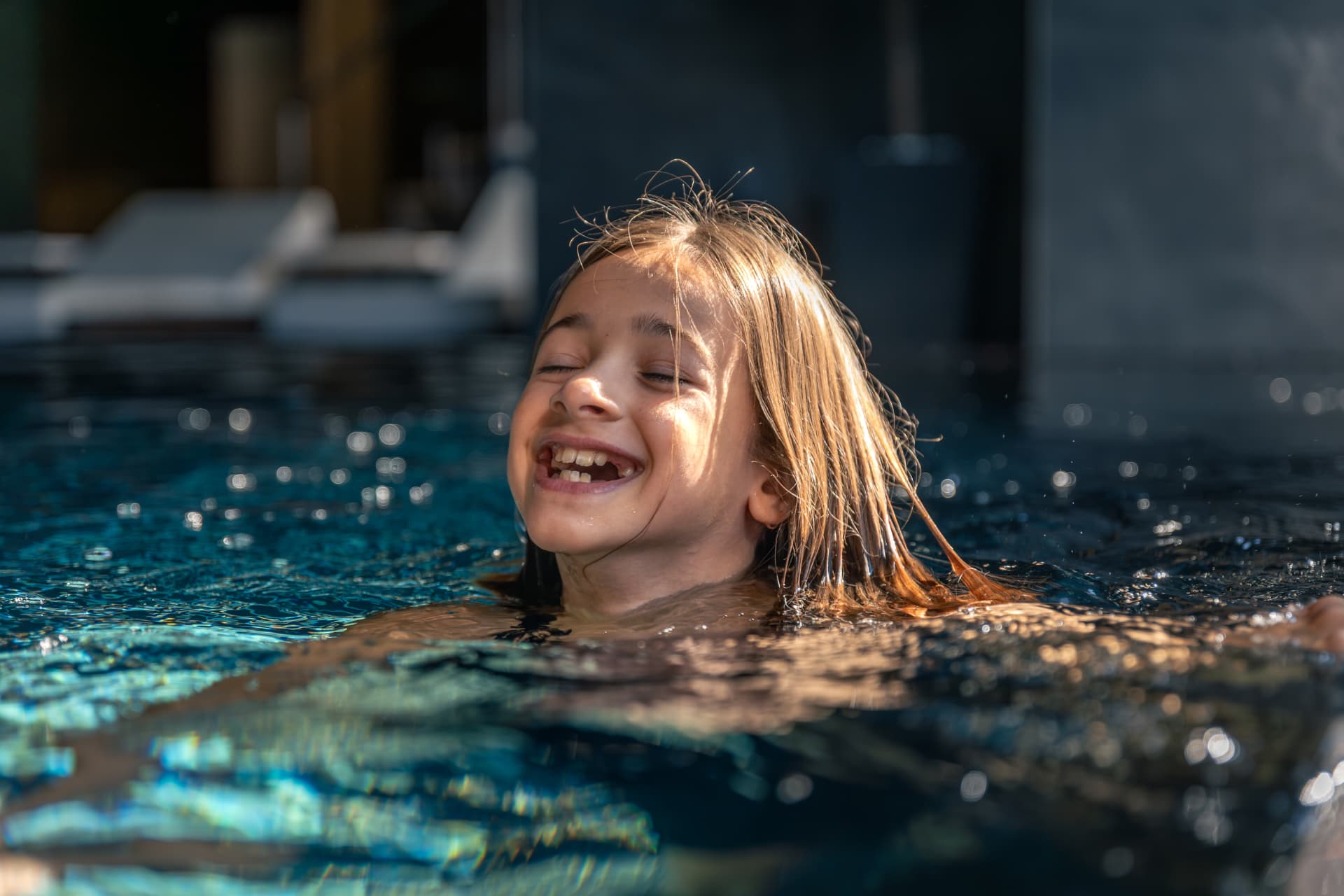 Child laughing while swimming in a sunlit pool