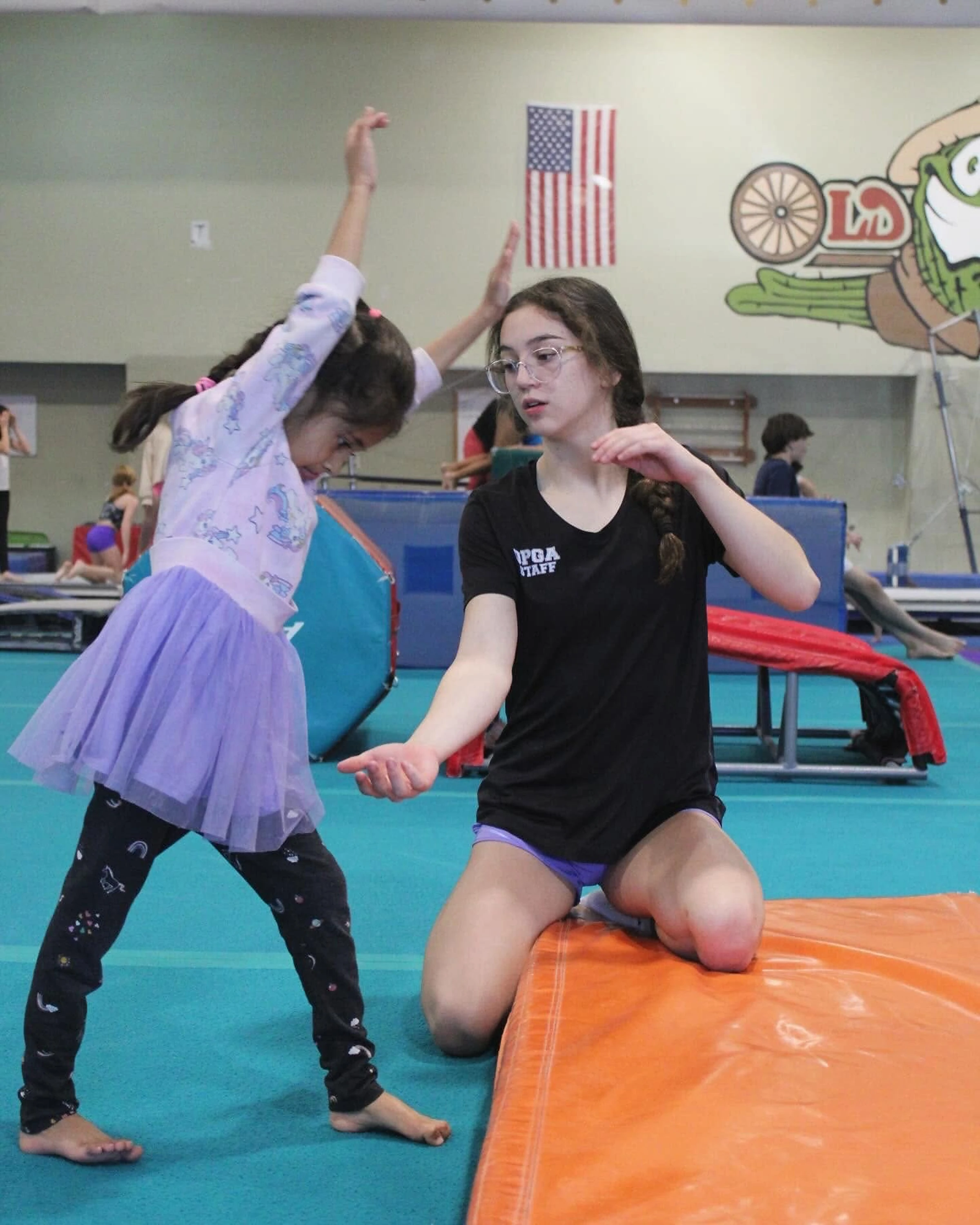 A coach working with a young gymnast at Old Pueblo